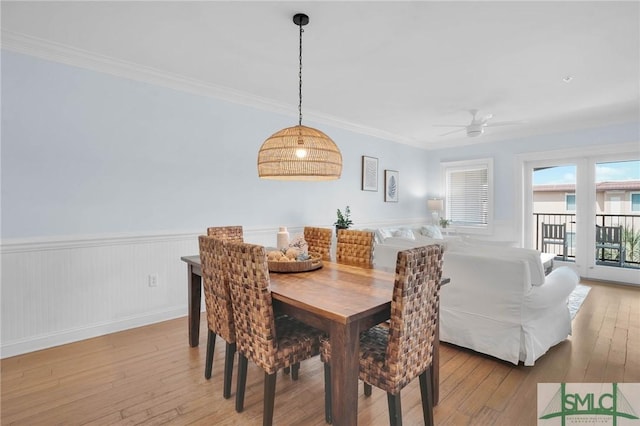 dining space with wainscoting, crown molding, a ceiling fan, and hardwood / wood-style flooring