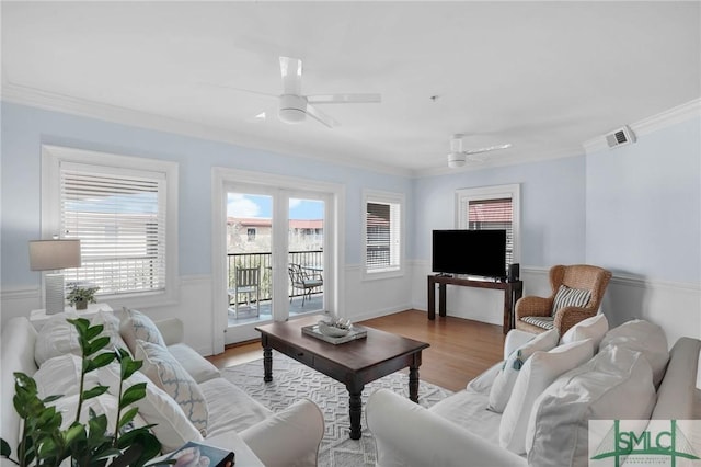 living area featuring visible vents, plenty of natural light, ceiling fan, and ornamental molding