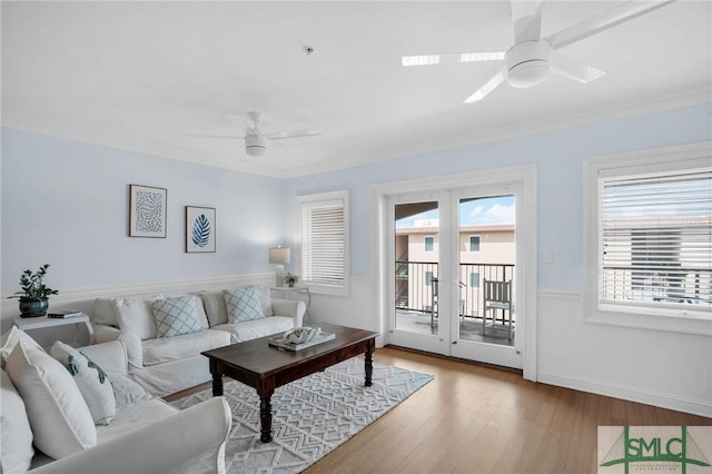 living area with baseboards, crown molding, ceiling fan, and wood finished floors