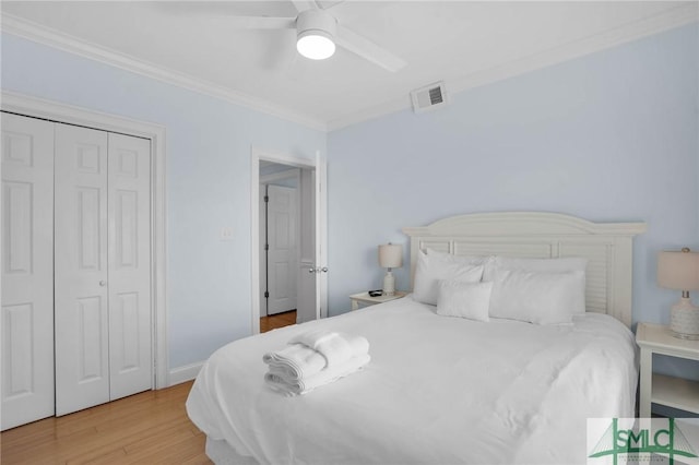 bedroom with wood finished floors, visible vents, ceiling fan, a closet, and crown molding