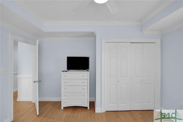 unfurnished bedroom with crown molding, baseboards, light wood-type flooring, a closet, and a ceiling fan