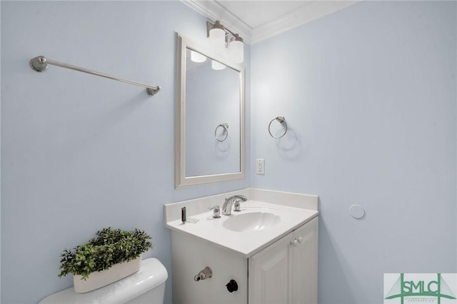 bathroom featuring toilet, vanity, and ornamental molding