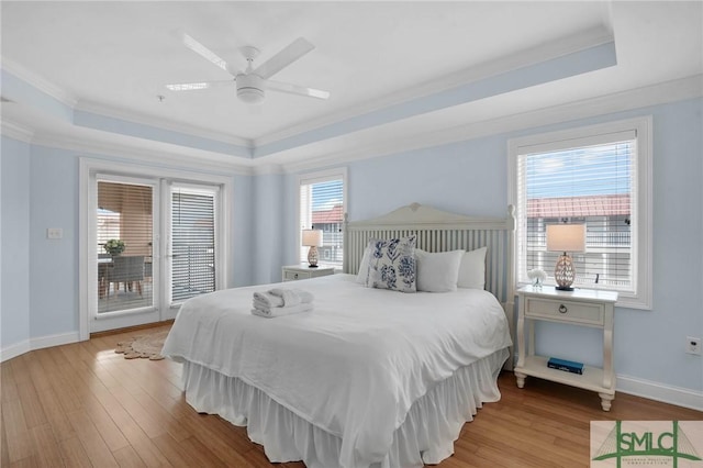 bedroom featuring a tray ceiling, wood finished floors, and ornamental molding