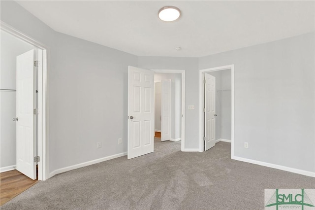 unfurnished bedroom featuring a closet, a walk in closet, and baseboards