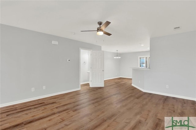 unfurnished living room with visible vents, baseboards, wood finished floors, and ceiling fan with notable chandelier