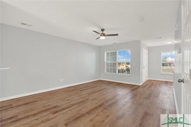 spare room featuring visible vents, wood finished floors, baseboards, and ceiling fan