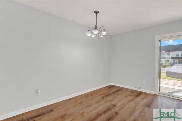 unfurnished dining area featuring a notable chandelier, wood finished floors, and baseboards