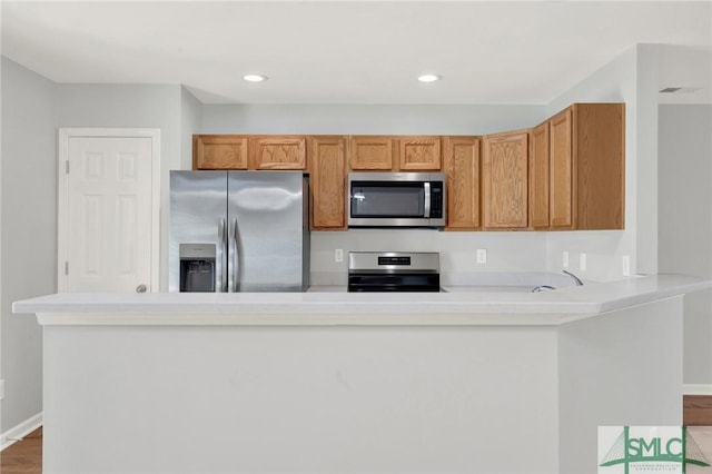 kitchen with wood finished floors, recessed lighting, stainless steel appliances, light countertops, and baseboards