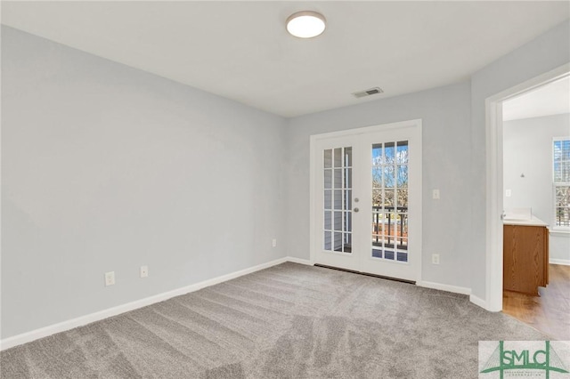 empty room with light carpet, visible vents, french doors, and baseboards