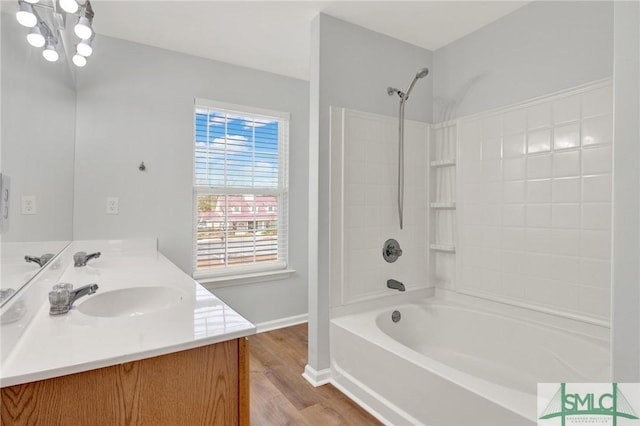 bathroom with double vanity, wood finished floors, bathing tub / shower combination, and a sink