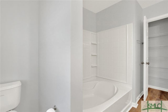 bathroom with toilet, walk in shower, a tub, and baseboards