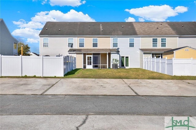 rear view of property with a lawn, central AC unit, and fence private yard