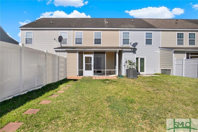 back of property with central air condition unit, a lawn, a fenced backyard, and a sunroom