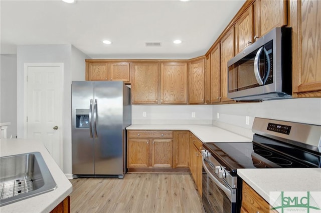 kitchen with stainless steel appliances, light wood-type flooring, and light countertops