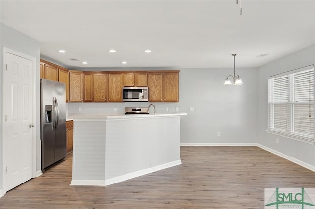 kitchen featuring recessed lighting, appliances with stainless steel finishes, brown cabinetry, light wood finished floors, and light countertops