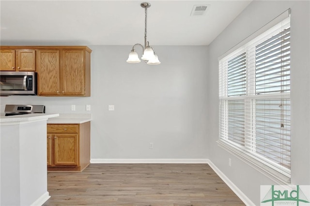 kitchen with visible vents, baseboards, light wood-type flooring, appliances with stainless steel finishes, and a notable chandelier