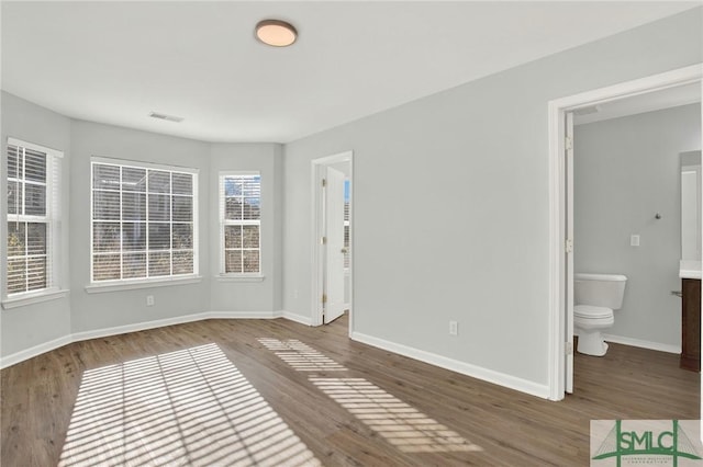 empty room featuring visible vents, wood finished floors, and baseboards