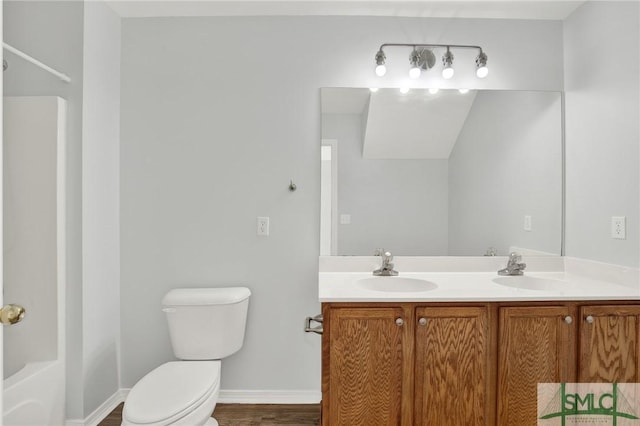 bathroom with a sink, baseboards, toilet, and double vanity