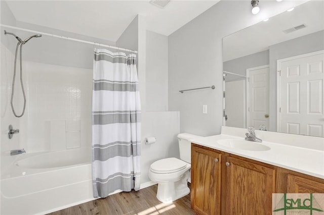 bathroom featuring visible vents, toilet, shower / bath combo with shower curtain, wood finished floors, and vanity