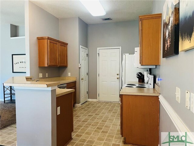 270 Lancaster Way, Richmond Hill, GA 31324 - kitchen featuring visible vents, a peninsula, range with electric cooktop, light countertops, and brown cabinets