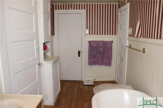 bathroom with a wainscoted wall, wallpapered walls, and wood finished floors