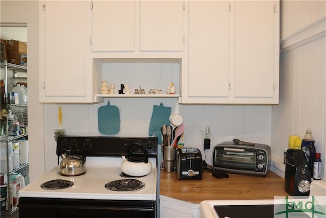 kitchen featuring electric range, wood finished floors, light countertops, and white cabinetry