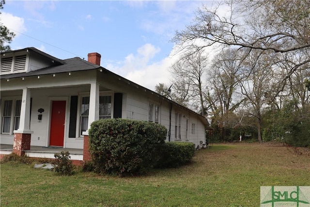 view of property exterior with a yard, covered porch, and a chimney