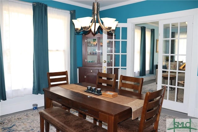 dining space featuring an inviting chandelier, a healthy amount of sunlight, french doors, and ornamental molding