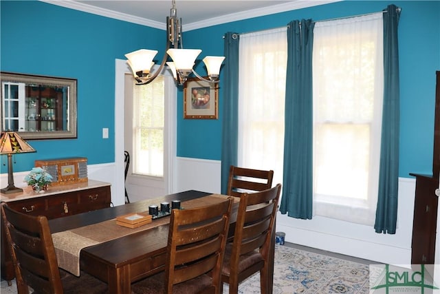 dining room featuring crown molding, a wainscoted wall, and a chandelier