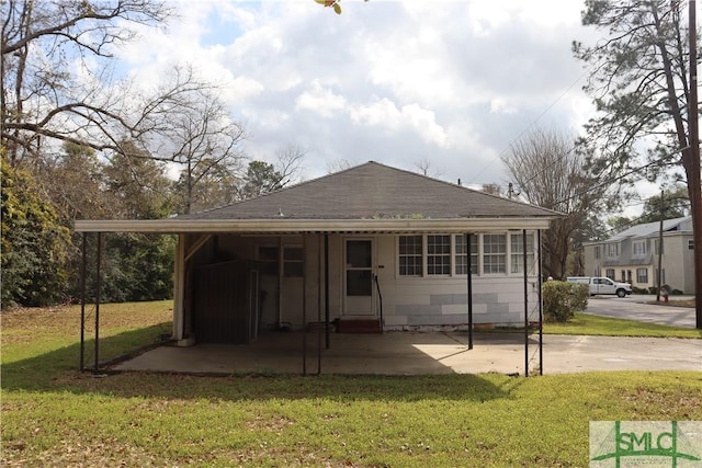 back of property with an attached carport and a yard