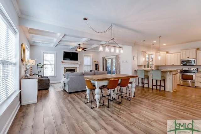 kitchen featuring beamed ceiling, appliances with stainless steel finishes, a breakfast bar area, and light wood finished floors