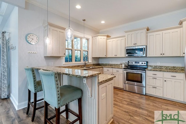 kitchen featuring a sink, a peninsula, crown molding, light wood finished floors, and stainless steel appliances