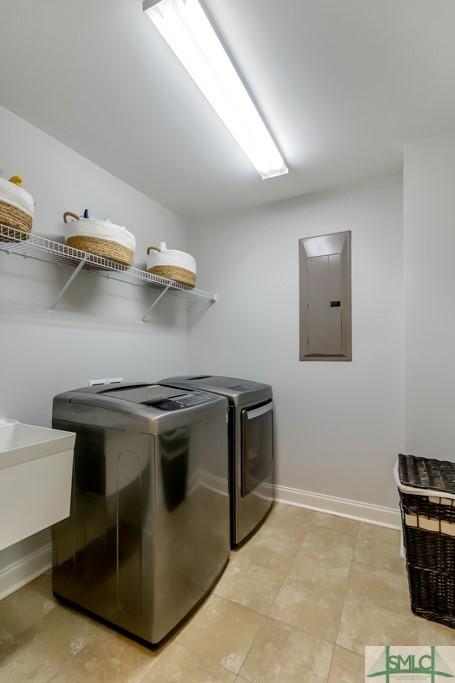 washroom featuring laundry area, separate washer and dryer, electric panel, a sink, and baseboards