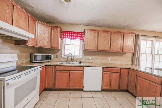 kitchen featuring white appliances, a sink, light countertops, under cabinet range hood, and a textured ceiling