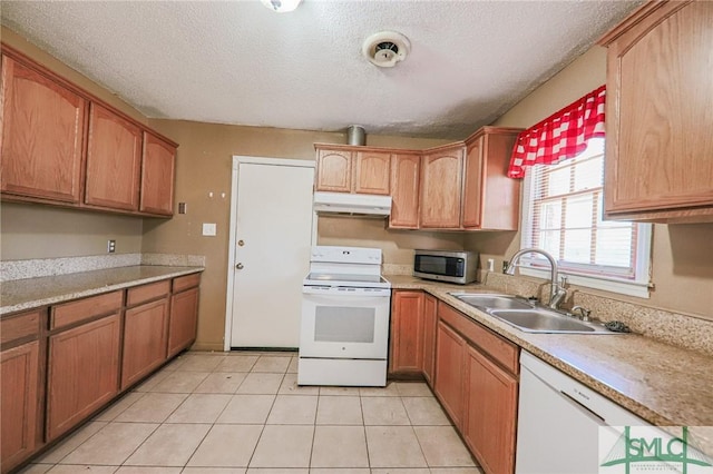 kitchen with under cabinet range hood, a sink, a textured ceiling, white appliances, and light countertops