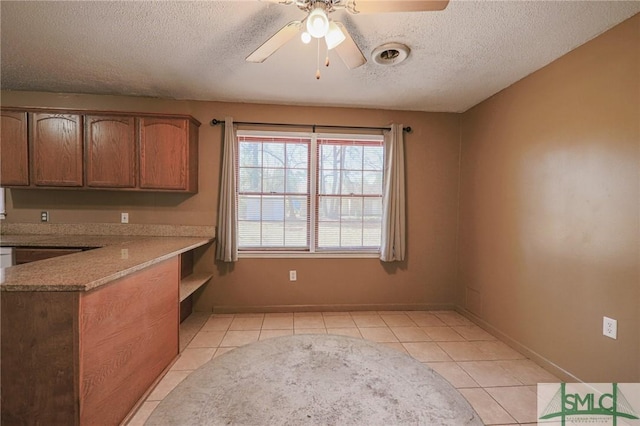 kitchen with light tile patterned floors, baseboards, a textured ceiling, and ceiling fan