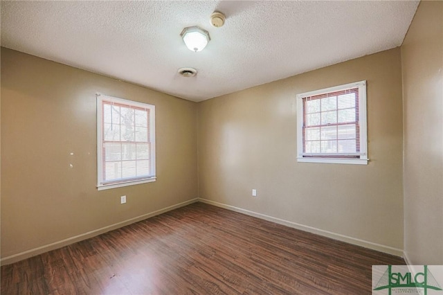 spare room with visible vents, a textured ceiling, baseboards, and wood finished floors