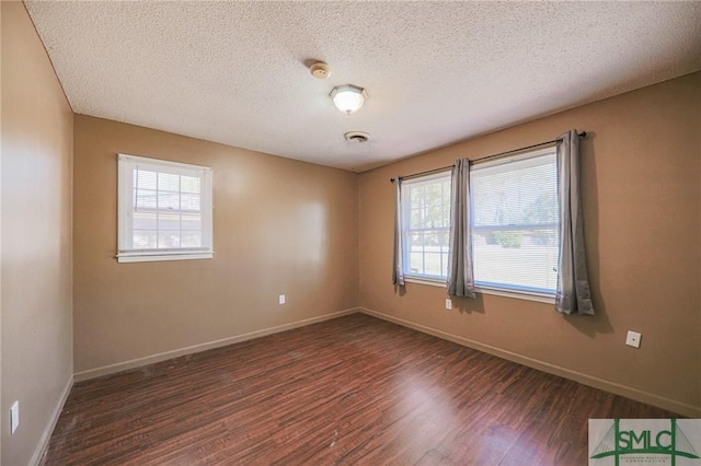 unfurnished room with a wealth of natural light, a textured ceiling, baseboards, and wood finished floors