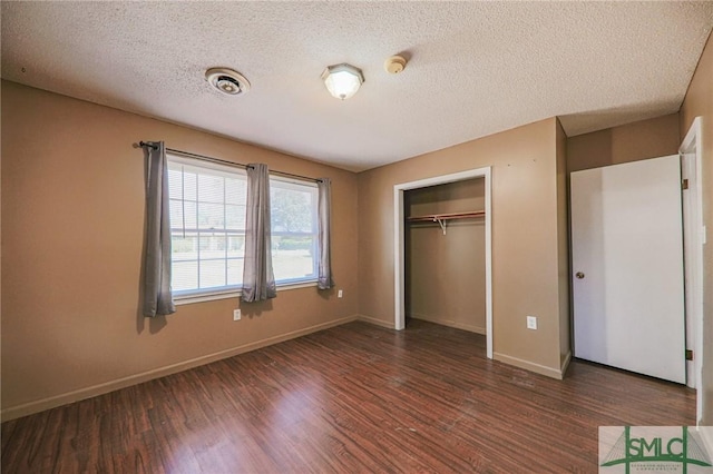 unfurnished bedroom featuring a closet, a textured ceiling, baseboards, and wood finished floors