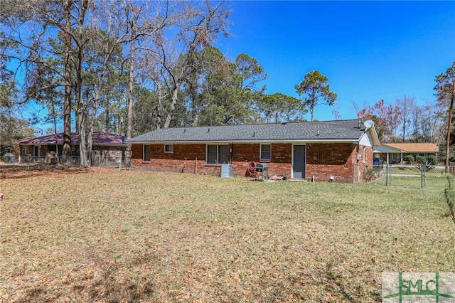 rear view of house with a yard, brick siding, and fence