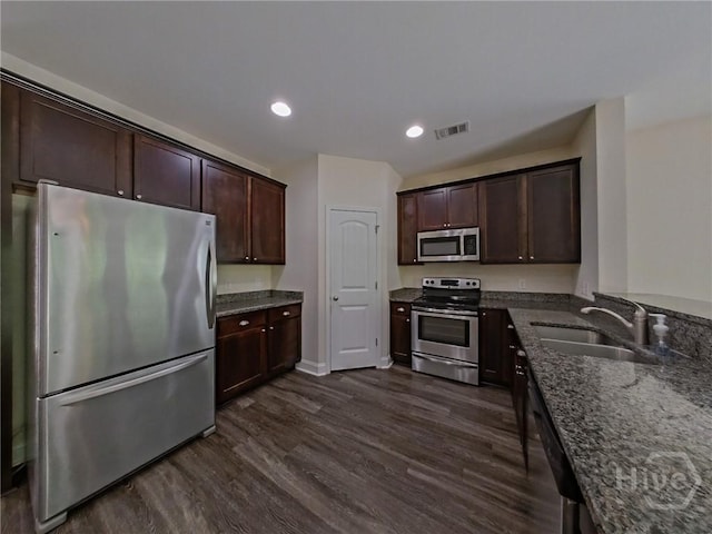 180 Kepler Loop, Richmond Hill, GA 31324 - kitchen with stainless steel appliances, a sink, dark stone countertops, dark wood-type flooring, and dark brown cabinets