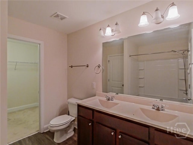 180 Kepler Loop, Richmond Hill, GA 31324 - full bathroom featuring wood finished floors, double vanity, toilet, a spacious closet, and baseboards