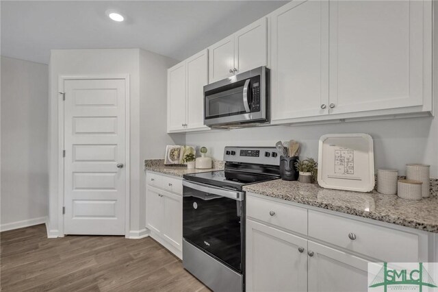 kitchen with white cabinets, appliances with stainless steel finishes, and light wood-style floors