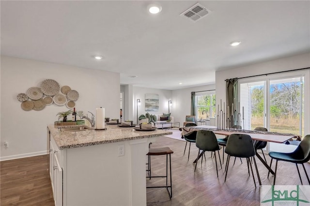 kitchen featuring light stone countertops, visible vents, a sink, dark wood-type flooring, and white cabinets