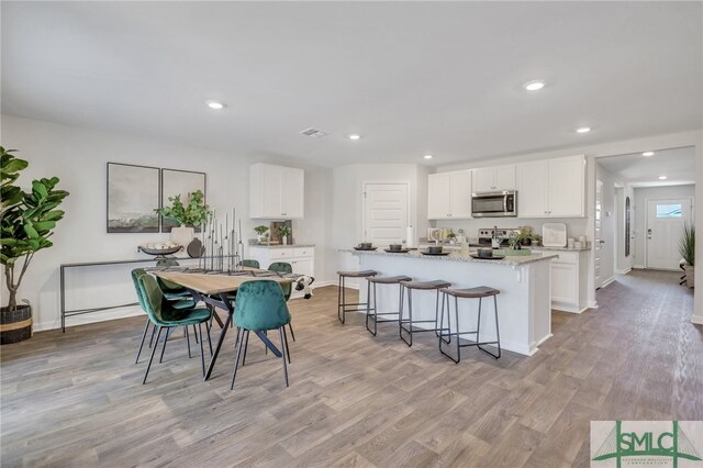 dining room featuring light wood finished floors, visible vents, recessed lighting, and baseboards