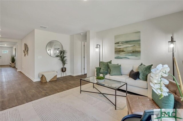 living room featuring visible vents, baseboards, and wood finished floors