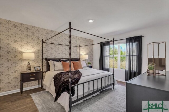 bedroom with baseboards, wood finished floors, and wallpapered walls