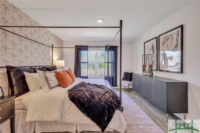 bedroom with light wood finished floors and wallpapered walls