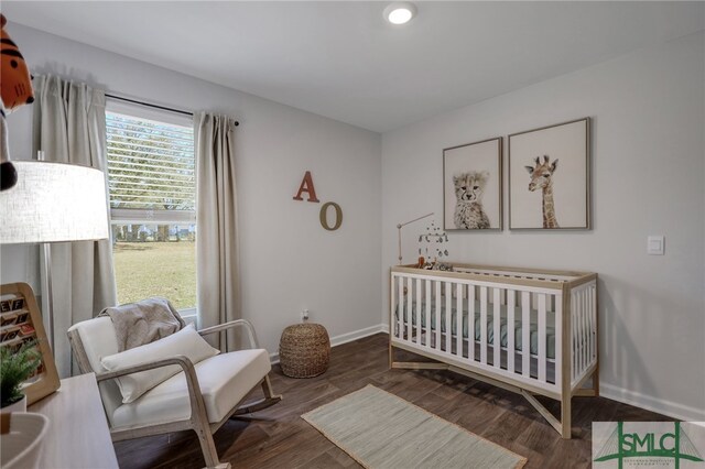 bedroom featuring a crib, baseboards, and wood finished floors