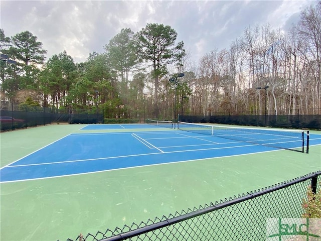 view of tennis court with community basketball court and fence